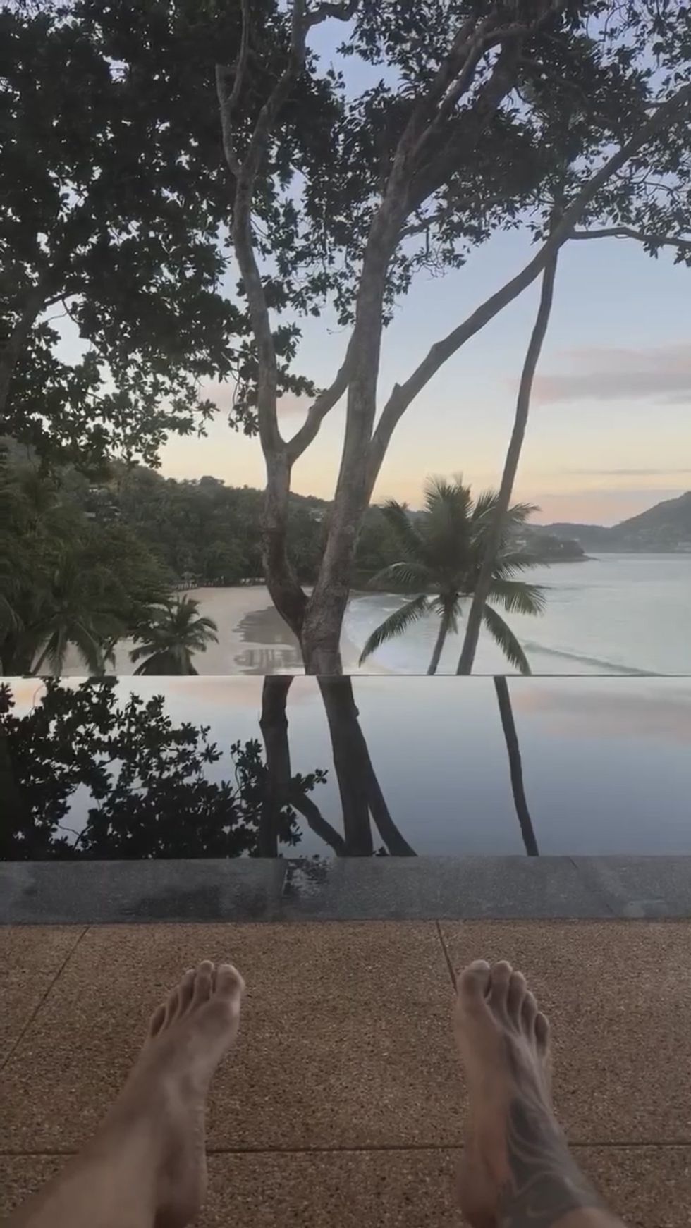 A POV of Ricky Martin's feet as he sits on a patio by the beach.