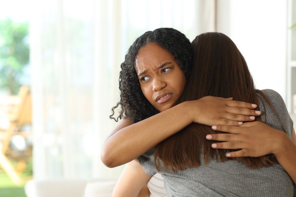 Disappointed false black woman hugging her friend at home