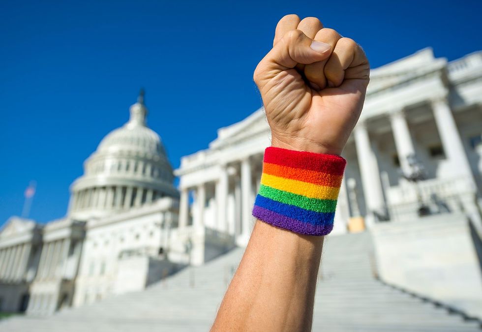 Hand wearing rainbow lgbtq pride wristband making a power fist gesture in front of the US Capitol Building in Washington DC USA