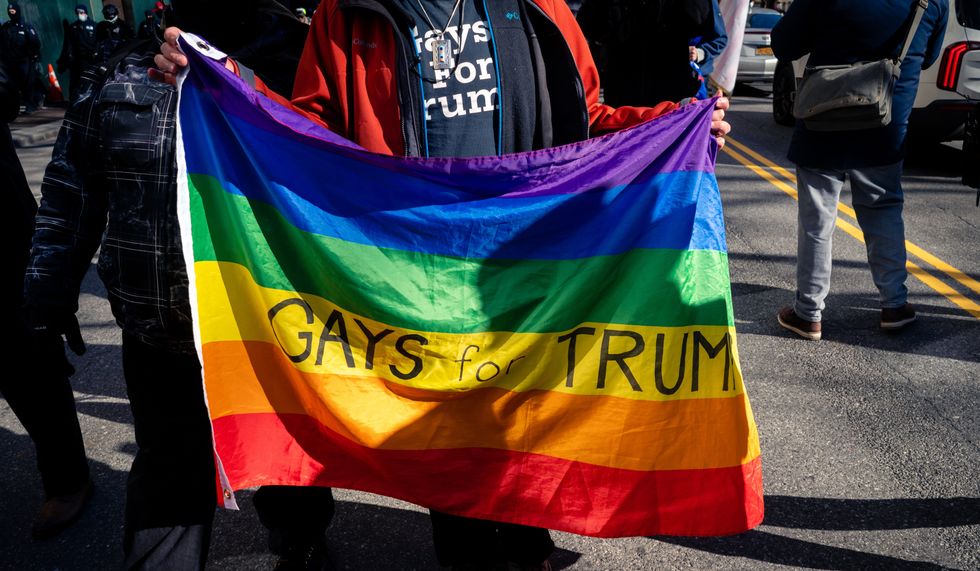 Man hold a rainbow flag with "Gays or Trump" written on it