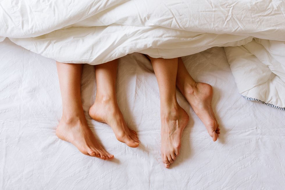 Women's feet sticking out of the blankets on a bed