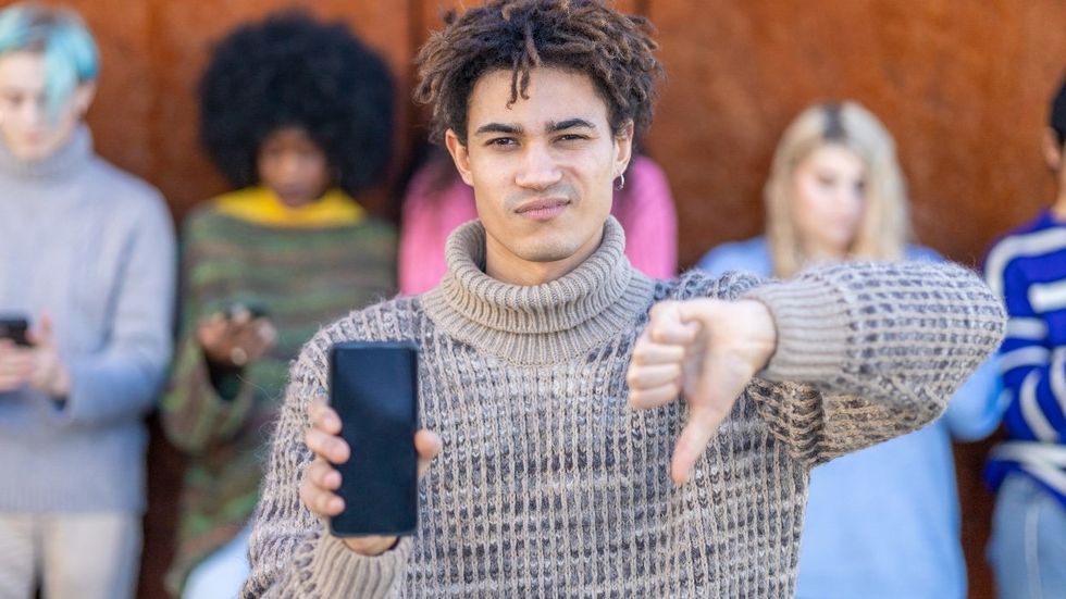 Young man with cellphone pointing down