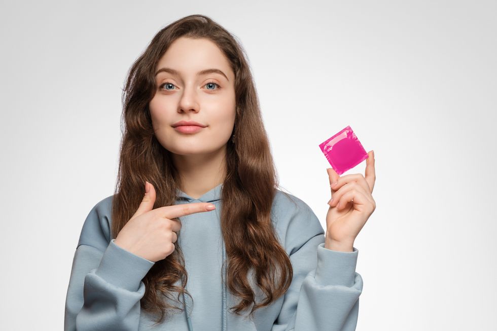 Young woman holding a condom